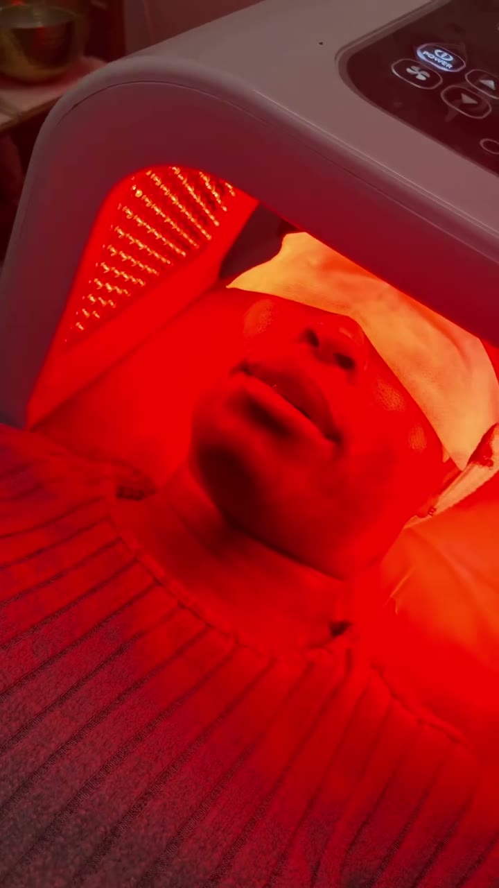 Client under a red LED light therapy panel